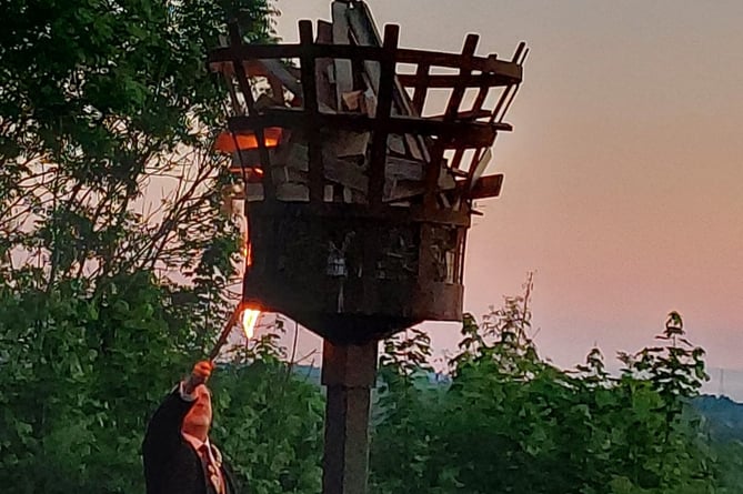 A photo of Ross Mayor Ed O’Driscoll lighting the beacon on The Prospect for the Queen’s platinum jubilee at sunset.