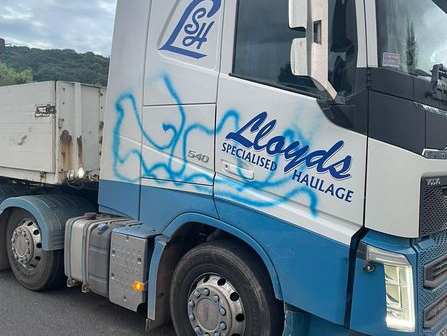 A photograph of spray-paint graffiti across the door of a truck.