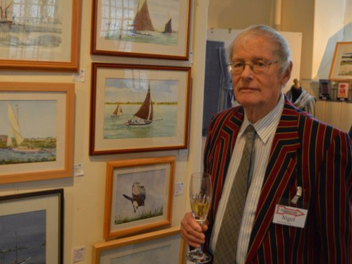 A photo of artist Nigel Street at Made in Ross, Private View, next to his watercolour paintings.