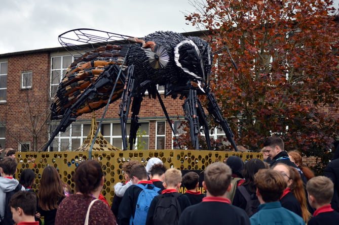 Students at John Kyrle High School crowded round a statue of a worker bee made of guns and knives