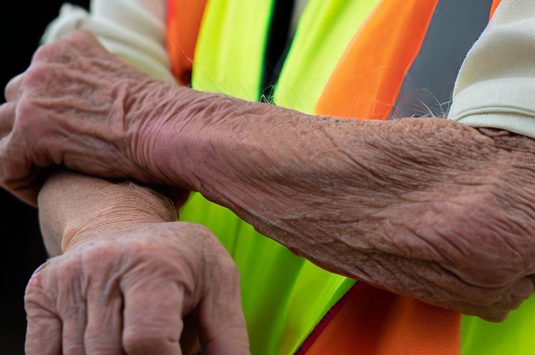 Older person rolling up sleeves in hi-vis