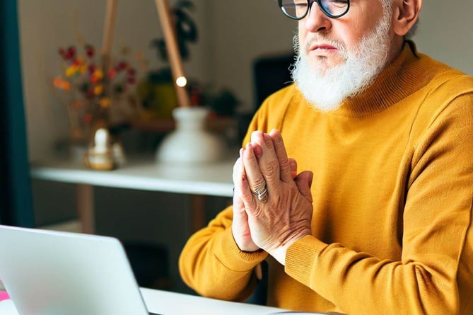A bearded man praying in front of the computer