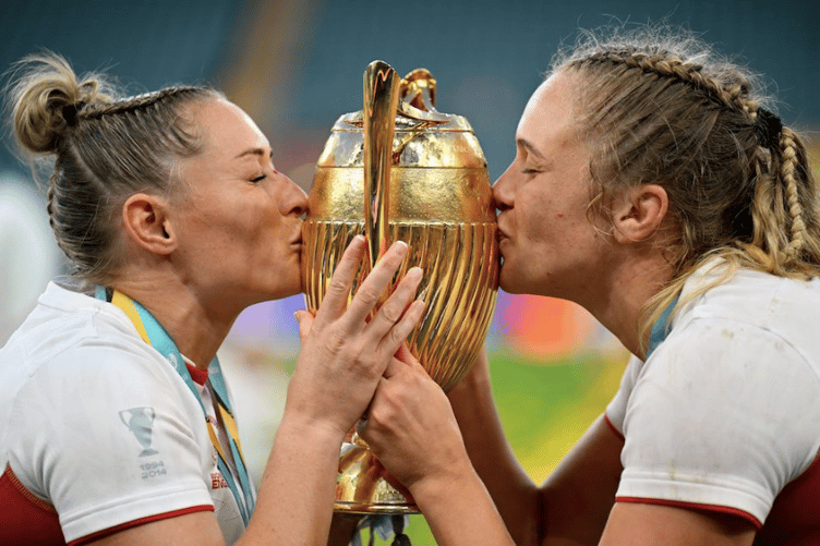 Zoe Aldcroft and Natasha “Mo” Hunt, left, share a triumphant moment, kissing the Women’s Rugby World Cup trophy after England’s 33–13 win over Canada.