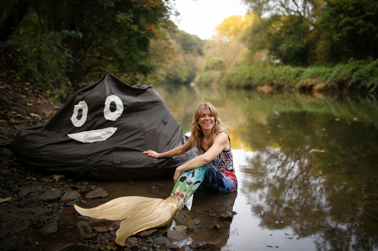 Lindsey Cole in her mermaid tail, towing a big poo sculpture.