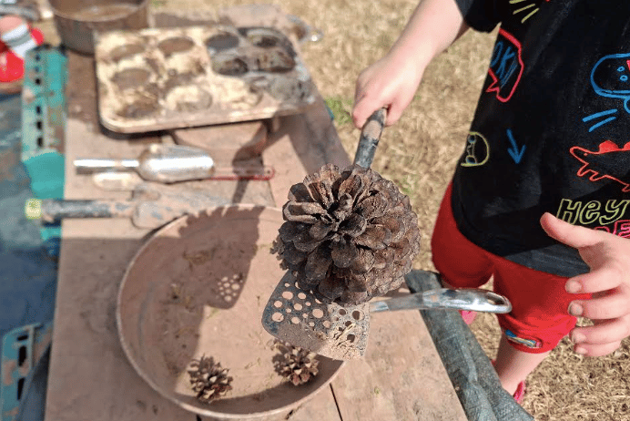 A youngster explores nature with pine cones during a WildPlay session in Bromyard, funded by Platform Housing Group and organised by Herefordshire Wildlife Trust.